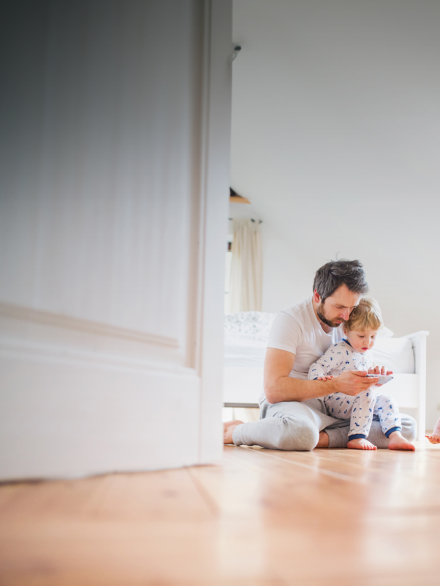 Mom and daughter playing with tablet on hard surface floor